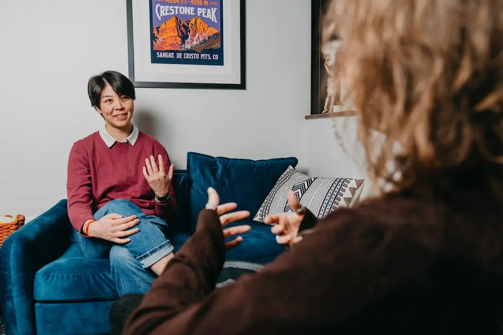 Individual therapy session in an LGBTQIA+ affirming mental health treatment setting, with a client and clinician engaged in conversation.