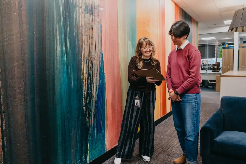 Chroma Wellness staff member reviewing information on a tablet with a client in the treatment center hallway.