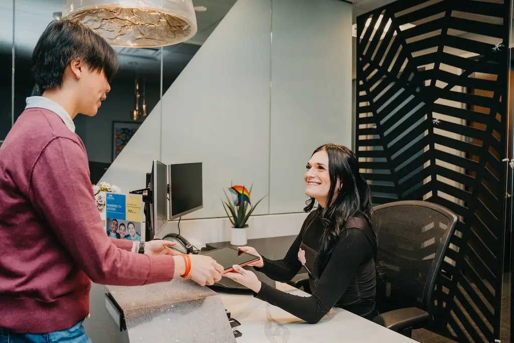 Client checking in at the reception desk at Chroma Wellness Center, an LGBTQ+ affirming outpatient mental health treatment center in Denver.