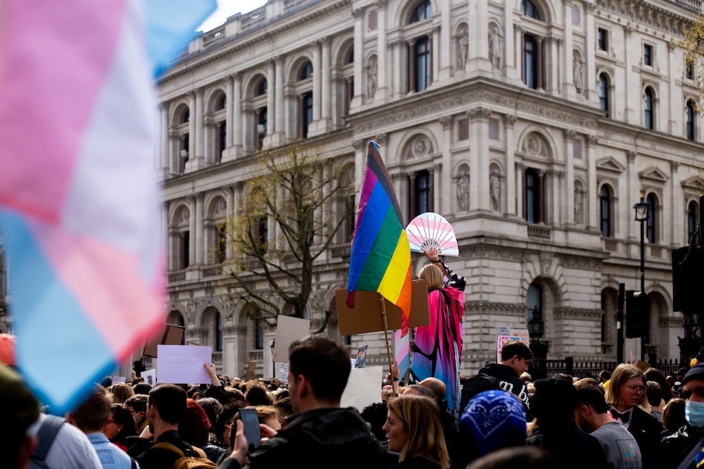 LGBTQIA+ pride flag raised in a public demonstration, reflecting advocacy for identity-affirming care and rejection of conversion therapy