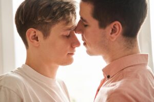 Two men standing closely face-to-face in an intimate moment, representing connection and emotional closeness in the context of anxiety and relationships