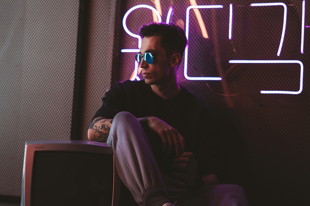 A person sitting beside neon lights in a dimly lit room, reflecting the emotional and nightlife-related themes discussed in chemsex and LGBTQ+ mental health conversations.