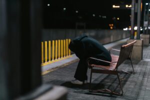 Person sitting hunched over on a bench at night, illustrating the fatigue and comedown effects that can occur after MDMA use.
