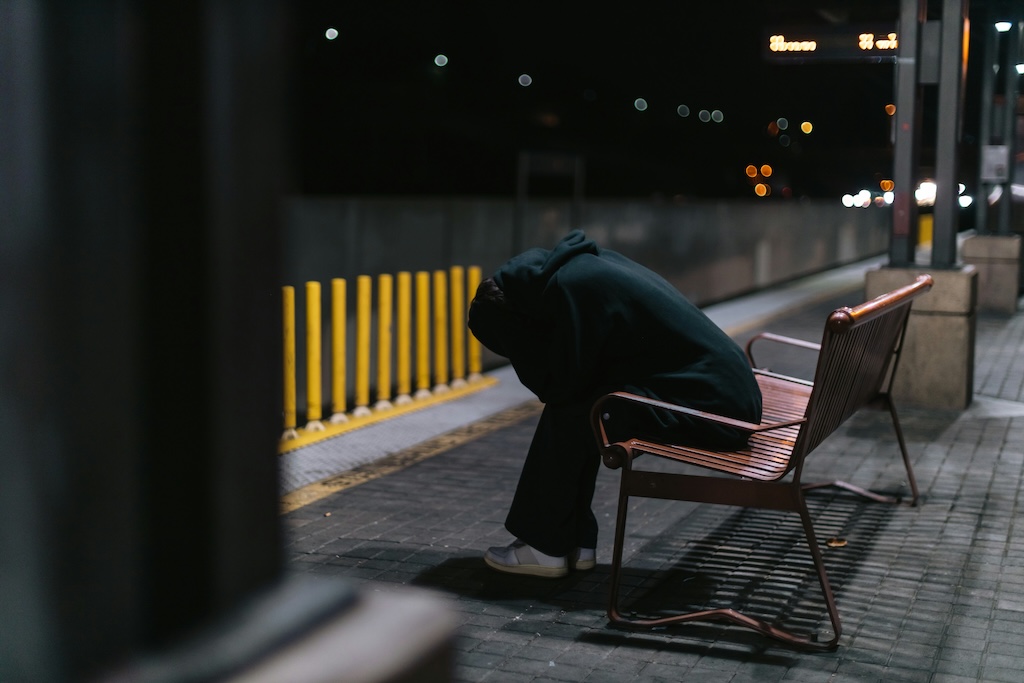 Person sitting hunched over on a bench at night, illustrating the fatigue and comedown effects that can occur after MDMA use.