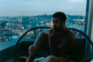 Person sitting by a window in quiet reflection, representing the emotional impact of substance use and mental health challenges.