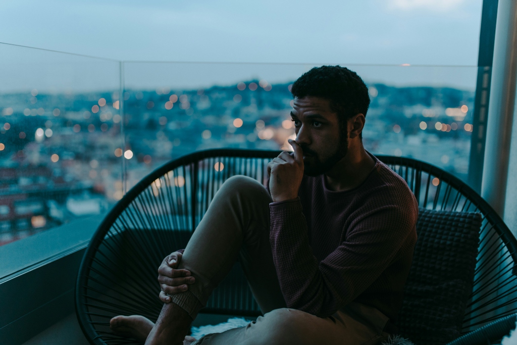 Person sitting by a window in quiet reflection, representing the emotional impact of substance use and mental health challenges.